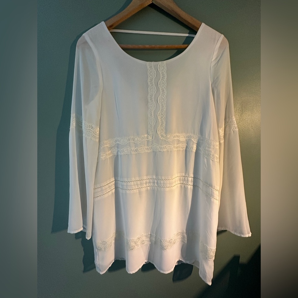 White mini dress with lace appliqué details and bell sleeves.